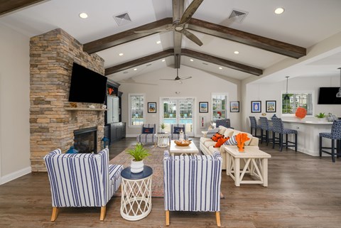A living room with a stone fireplace and striped chairs.