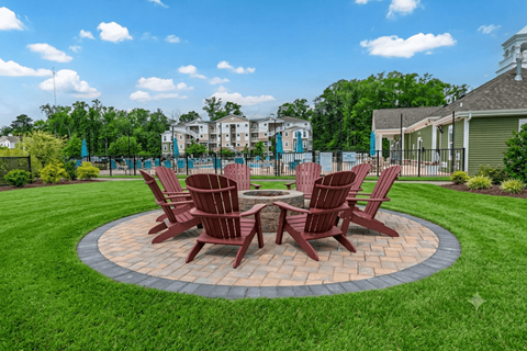 A set of four brown chairs are arranged around a circular table in a grassy area.