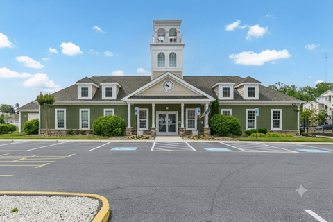 Clubhouse and a clock tower is surrounded by a parking lot.