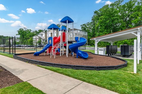 A playground with a blue and red slide and a white canopy.