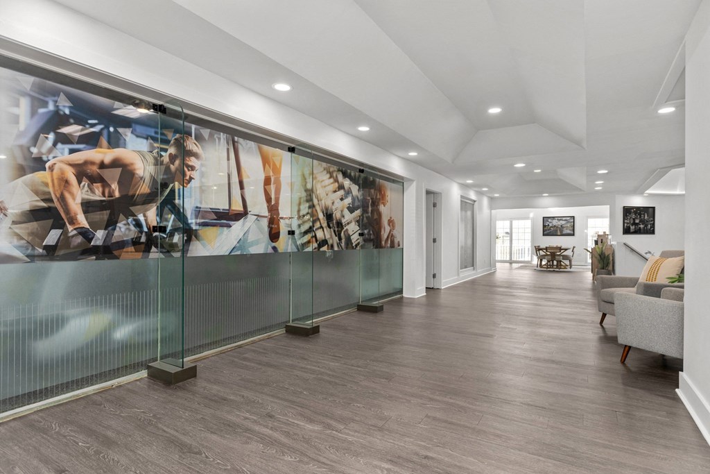 A wall mural of a man exercising is displayed in a spacious room with wooden flooring and white walls. at Eagle Ridge Apartments, Monroeville, 15146