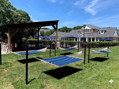 A blue hammock is strung between two poles in a grassy area.