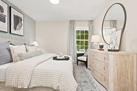 A bedroom with a large bed and a dresser with a mirror.