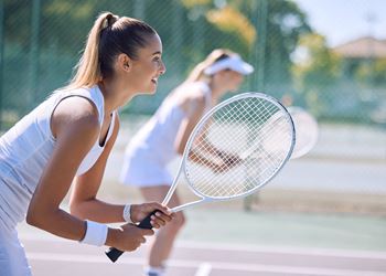 Two women playing tennis on a court.