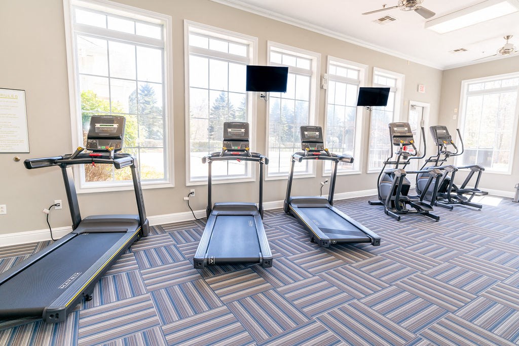 a fitness room with cardio machines and windows at The Ledges Apartment Homes, Groton, CT, 06340