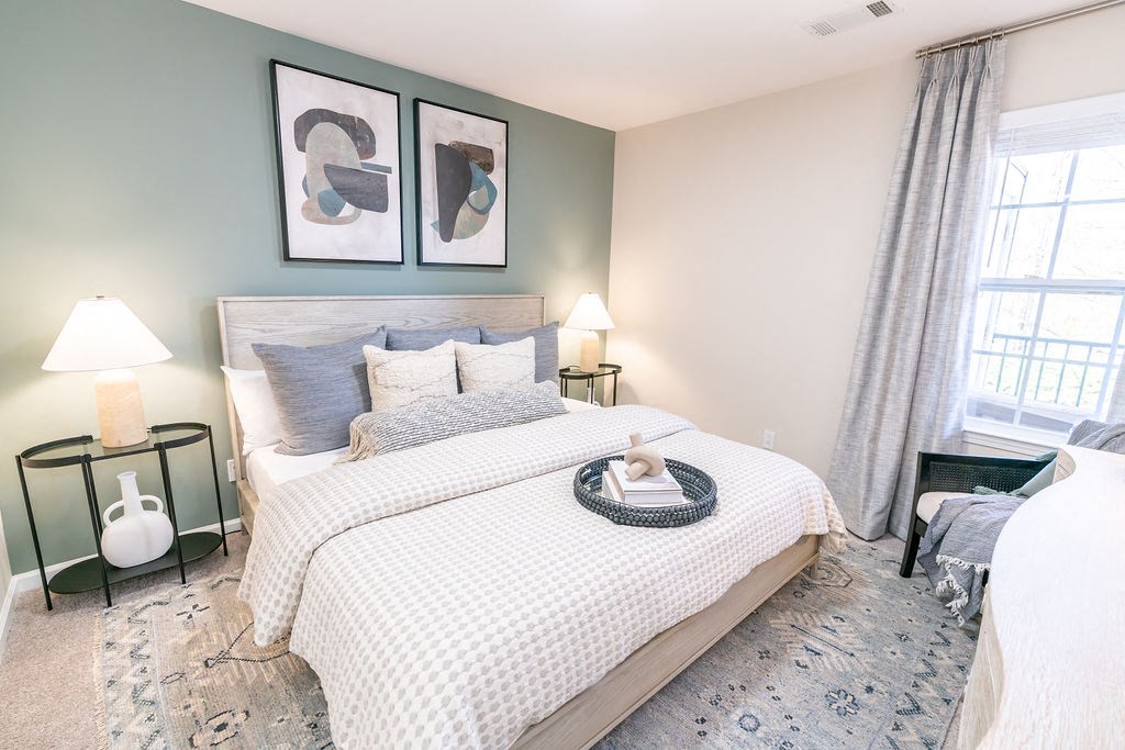 a bedroom with a bed and two windows at The Ledges Apartment Homes, Groton, CT, 06340