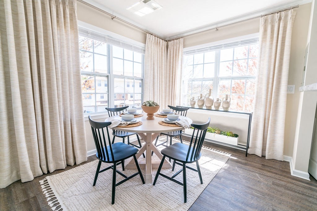 a dining room with a table and chairs and two windows at The Ledges Apartment Homes, Groton, CT, 06340