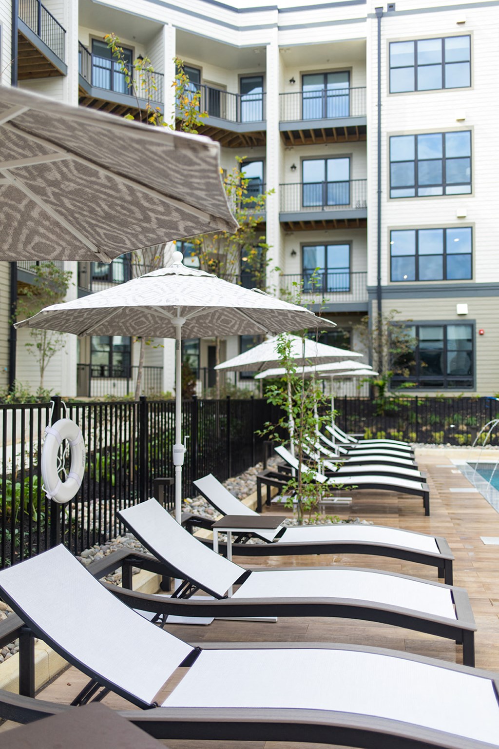 a row of lounge chairs and umbrellas in front of an apartment building at The Yards at Malvern, Malvern, PA
