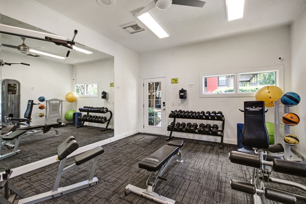 A gym with a variety of equipment including weights and exercise balls.