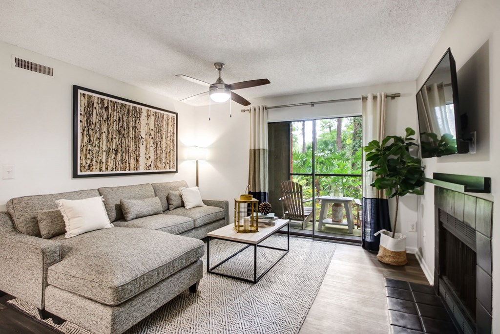 A living room with a grey couch, a coffee table, and a painting on the wall.
