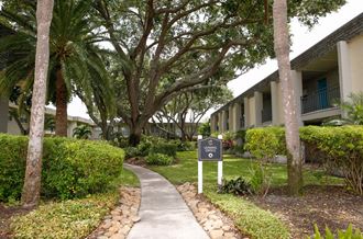 a pathway with a black and white sign in the middle of a grassy area with trees  at The Villas at Flagler Pointe, Saint Petersburg, 33712 - Photo Gallery 4