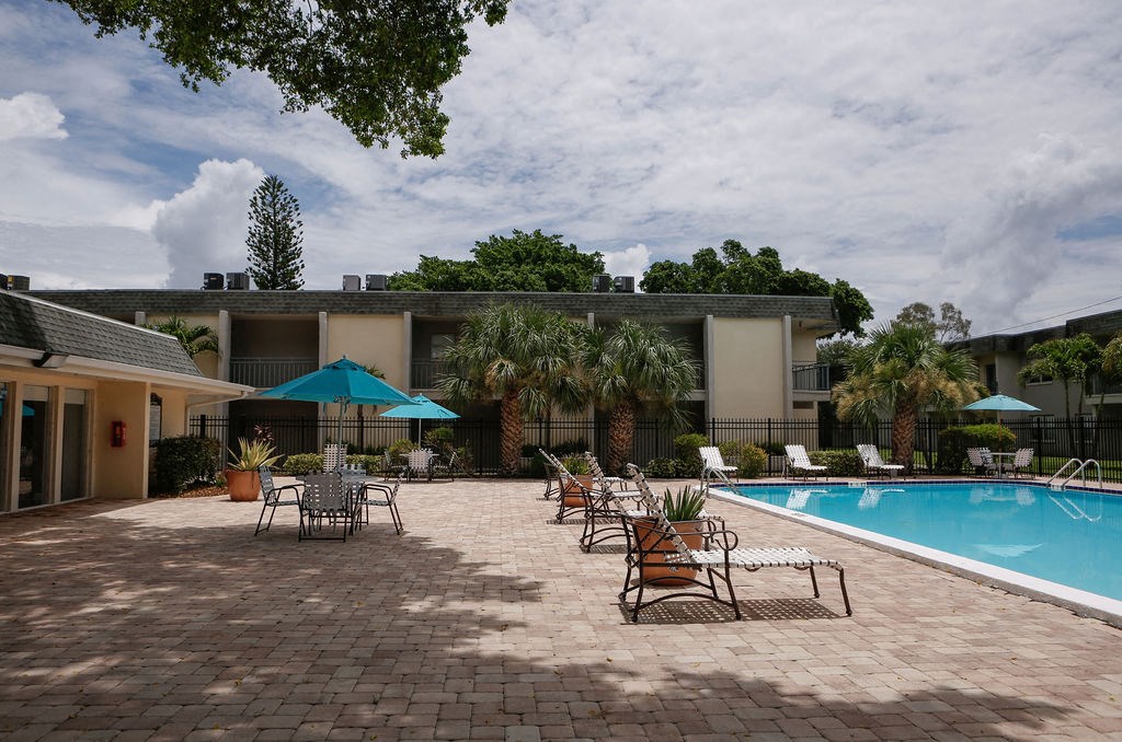 a swimming pool with lounge chairs and umbrellas in front of a building  at The Villas at Flagler Pointe, Saint Petersburg, FL