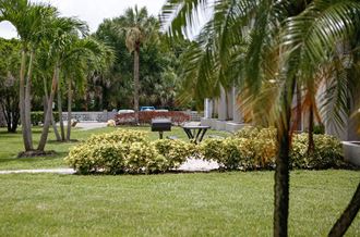 a picnic table in a grassy area with palm trees in the background  at The Villas at Flagler Pointe, Saint Petersburg, FL, 33712