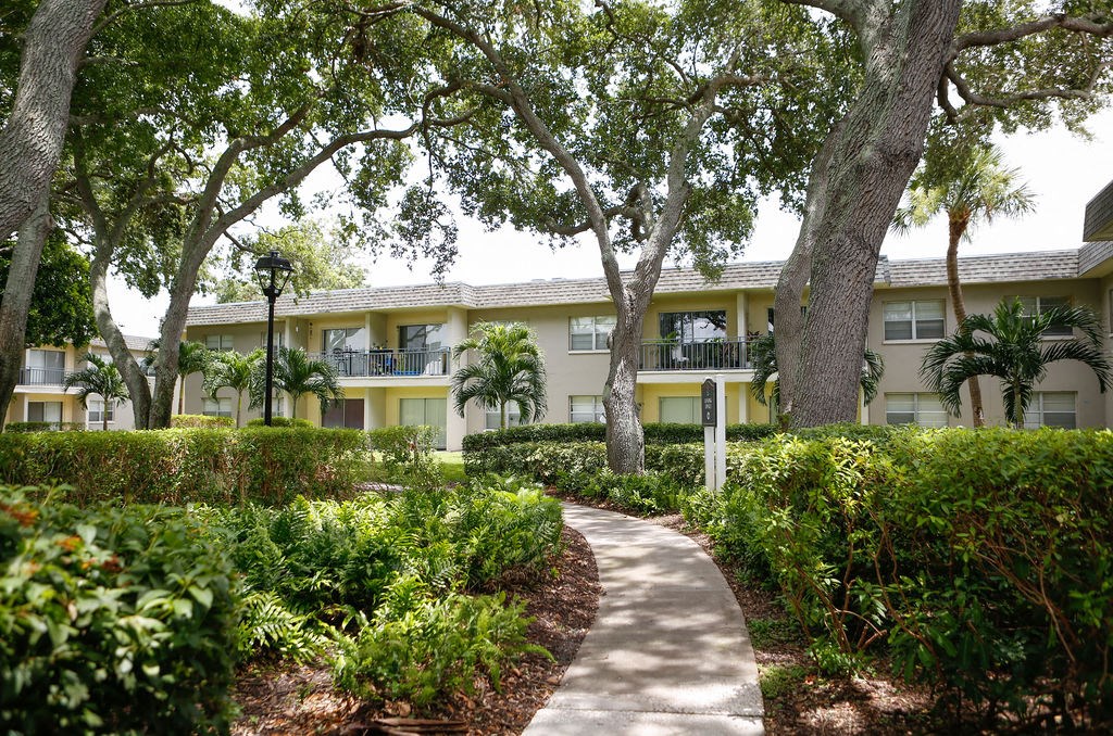 a pathway with trees and bushes in front of a building  at The Villas at Flagler Pointe, Saint Petersburg, FL