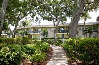 a pathway with trees and bushes in front of a building  at The Villas at Flagler Pointe, Saint Petersburg, FL - Photo Gallery 3