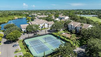 an aerial view of a tennis court with apartments in the background at Champions Walk Apartment Homes, Bradenton, Florida