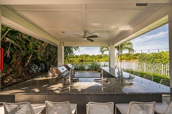 a covered patio with a bar and chairs and a water view at Champions Walk Apartment Homes, Bradenton, Florida
