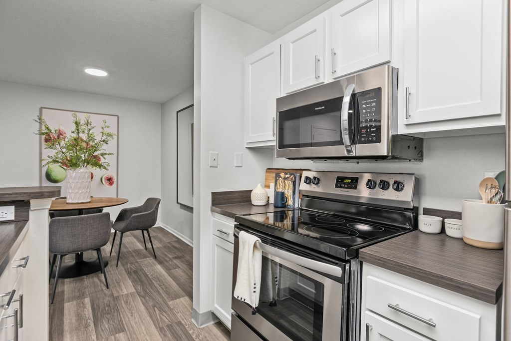 A modern kitchen with a stove top oven and microwave above it. at Eagle Ridge Apartments, Monroeville, PA