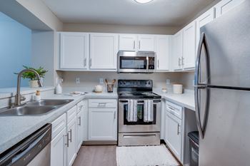 a kitchen with stainless steel appliances and white cabinets at The Monroe Apartment Homes, Florida, 32303