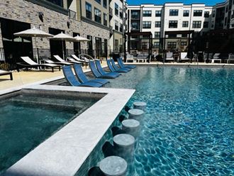 a swimming pool with blue lounge chairs next to a building