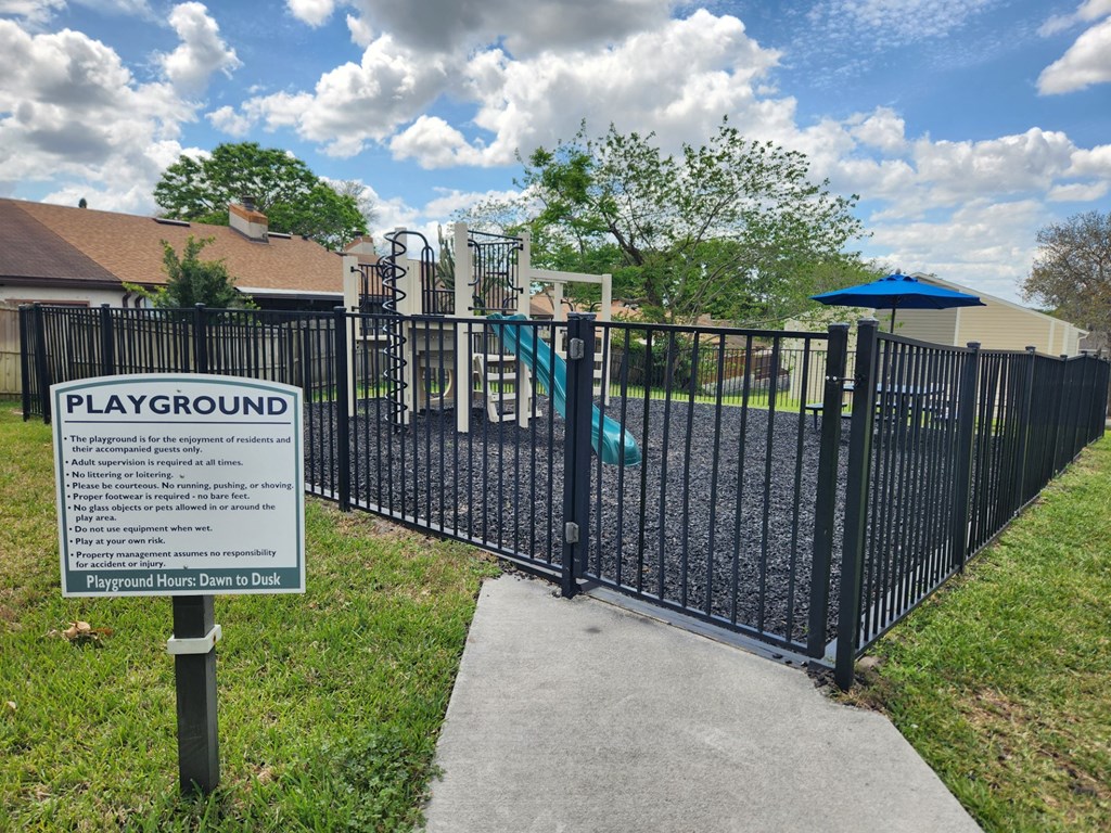 A sign on a playground gate provides information about the playground's rules and regulations.