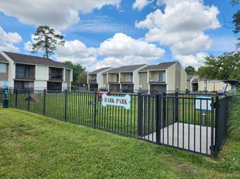 A row of apartment buildings with a sign that says Bark Park.