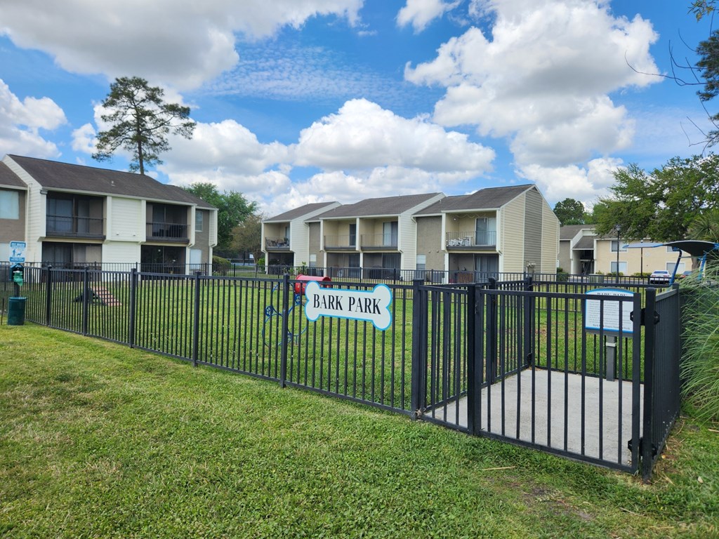 A row of apartment buildings with a sign that says Bark Park.