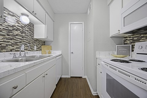 a kitchen with white cabinets and appliances and a stove and sink