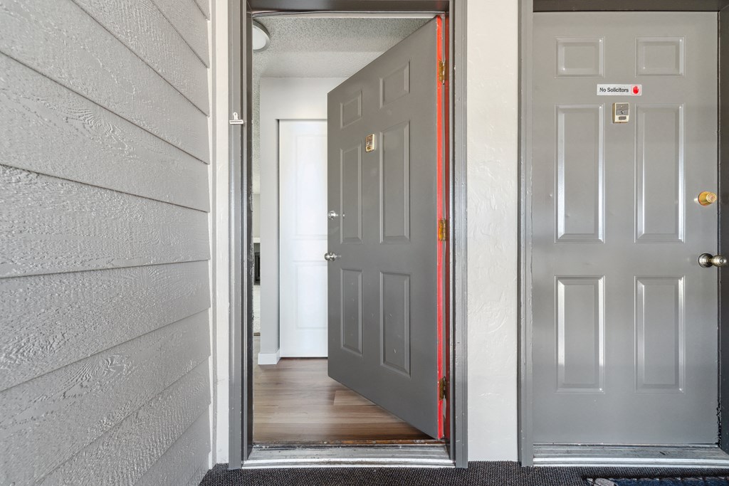 an open door leading to a hallway with a hardwood floor