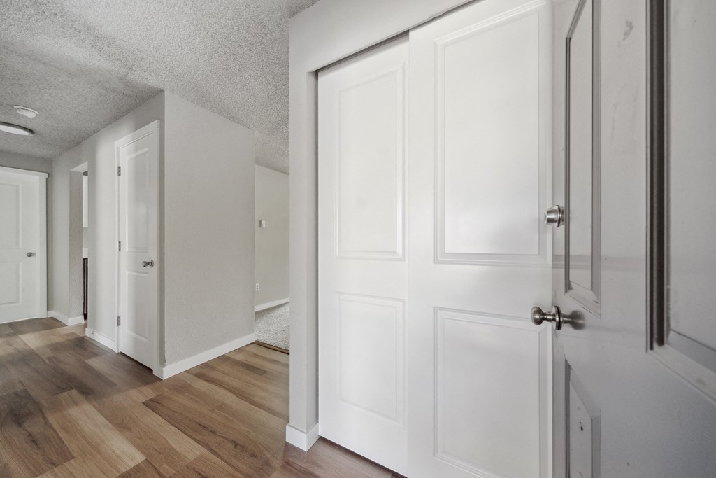 a bedroom with white doors and hardwood floors