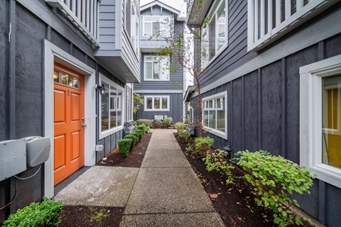 a walkway between two buildings with an orange door
