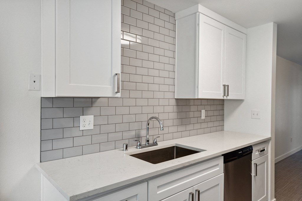 an empty kitchen with white cabinets and a sink