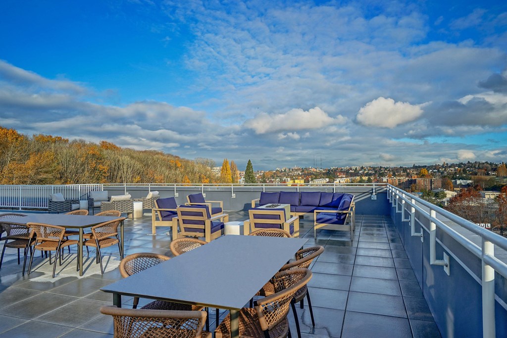 a rooftop patio with tables and chairs and a view of the city