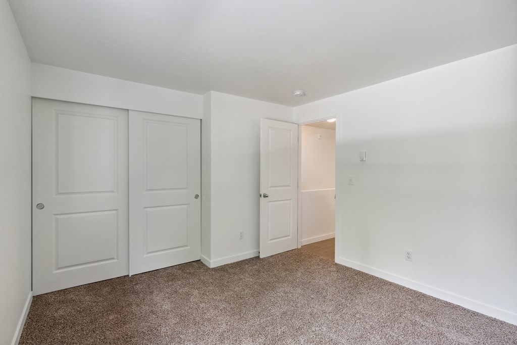 a bedroom with white doors and carpeting and white walls