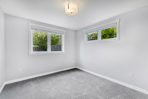 an empty room with two windows and a carpeted floor