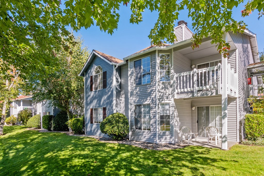 a blue and white house with a lawn and trees