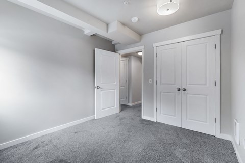 an empty bedroom with white doors and a closet