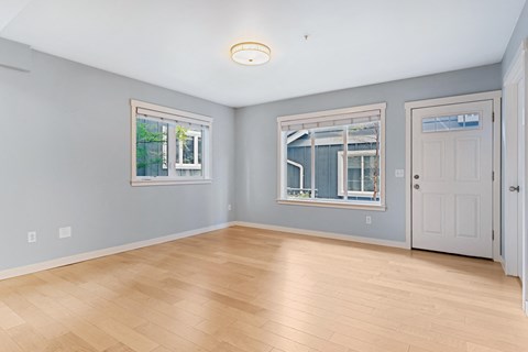 an empty living room with a hardwood floor and two windows