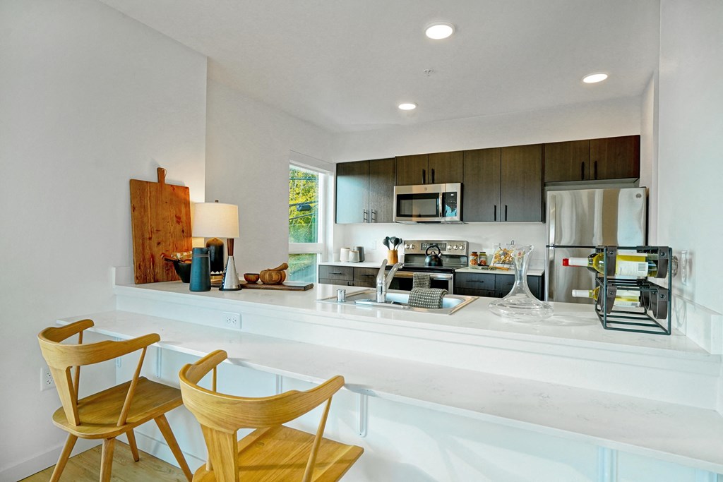 a kitchen with a bar and wooden chairs