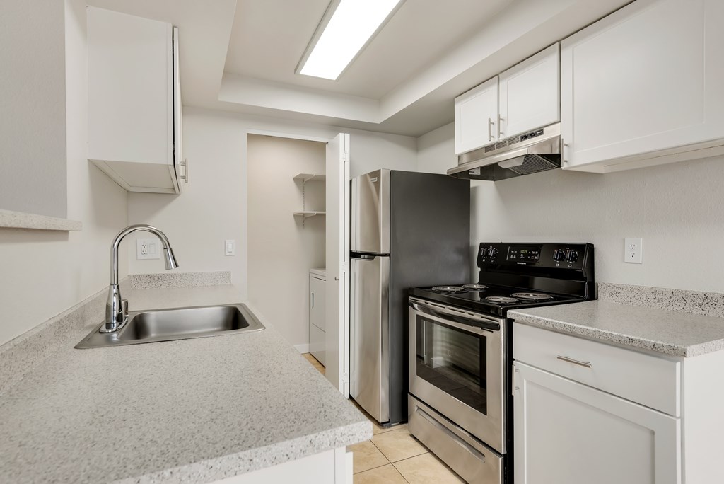 A kitchen with a sink, stove, and refrigerator.
