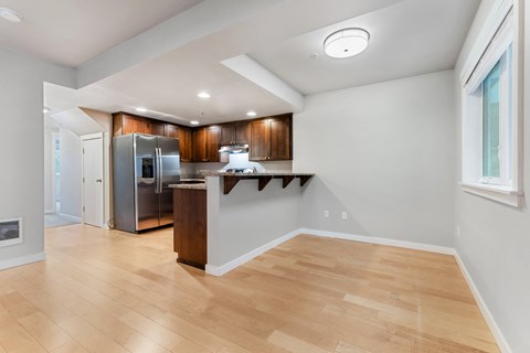 an open kitchen and living room with wood flooring and stainless steel appliances