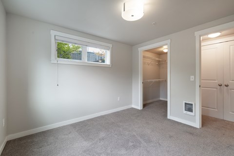 a bedroom with a closet and a window and a door to a bathroom