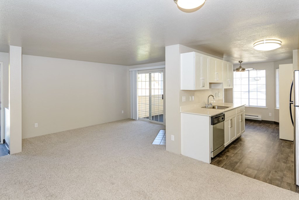 an empty living room and kitchen with a sink and a refrigerator