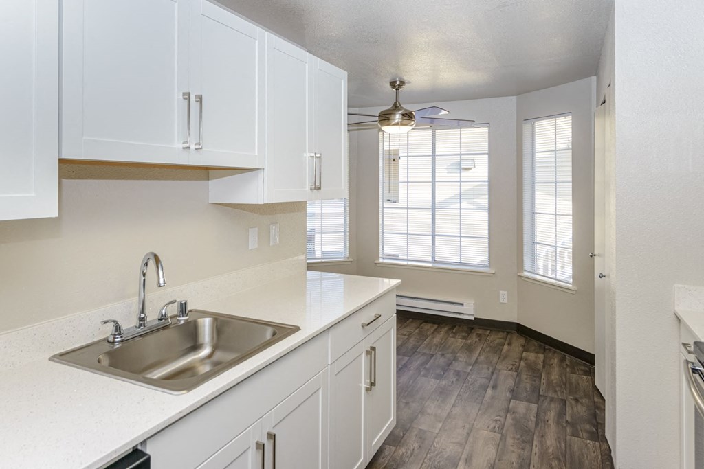 an empty kitchen with white cabinets and a sink