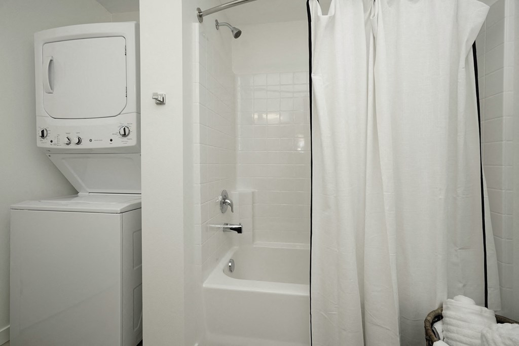 a small bathroom with a shower and a washer and dryer in it