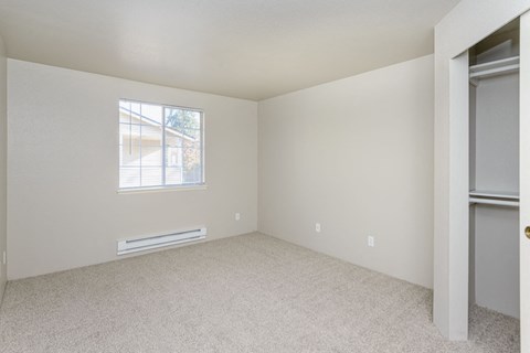 an empty bedroom with a window and a closet