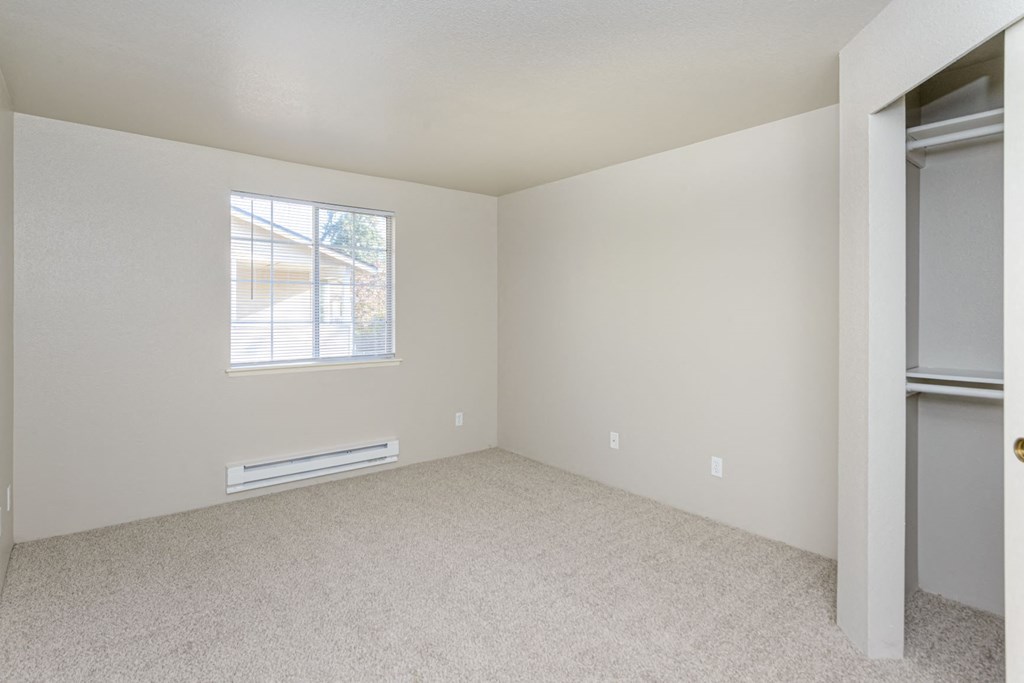 an empty bedroom with a window and a closet