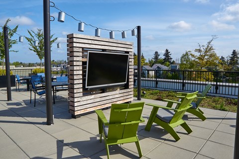 an outdoor patio with green chairs and a television on a wooden structure
