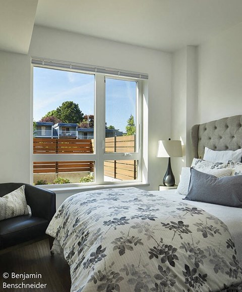 A bedroom with a large bed and a view of a balcony with a table and chairs.