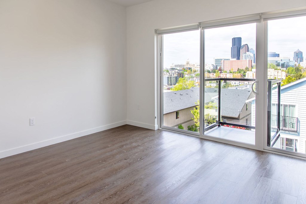 an empty living room with sliding glass doors and a view of the city